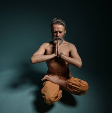 Gri sakallı yaşlı adam yoga yapıyor, pilates yapıyor, spor yapıyor, esneme egzersizleri yapıyor, asana havada duruyor ya da yerde denge çalışması yapıyor.