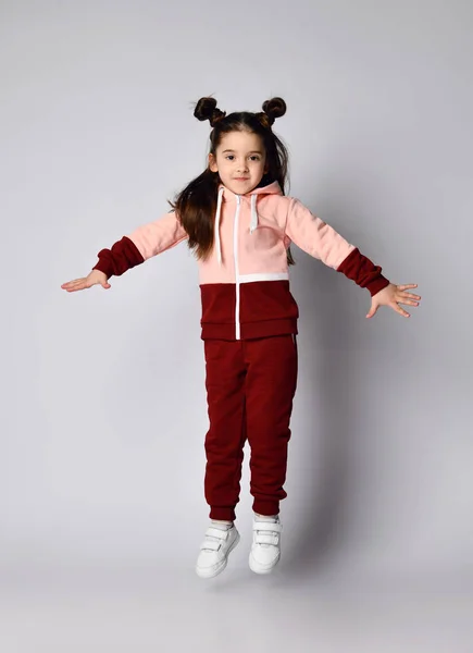 Frolic brunette kid girl in modern fashion pink brown sportwear is jumping having fun — Stock Photo, Image