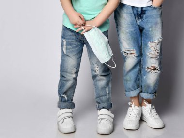 Koronavirüs salgınından korunmak için iki küçük kotlu kız ayakta ve ellerinde tıbbi maskeler var.