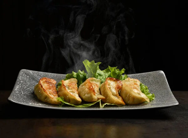 Gnocchi fritti giapponesi Gyoza con carne di maiale e verdure serviti su un piatto con fumo di vapore — Foto Stock