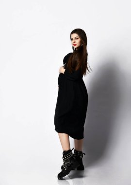 Siyah uzun elbiseli, uzun saçlı, zayıf, genç ve güzel hamile bir kadın. Hamilelik modası konsepti