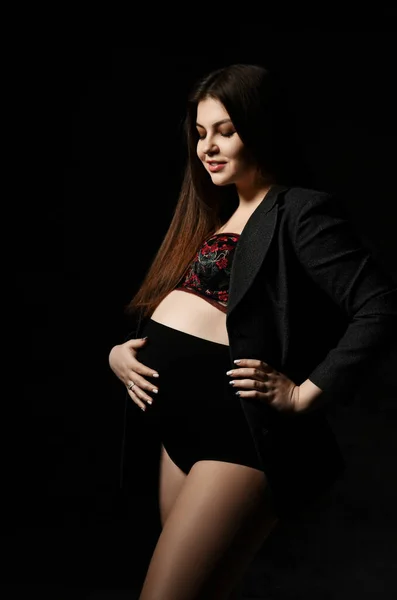 Jovem bela mulher grávida magra com cabelos longos em posar no fundo preto. Gravidez maternidade, esperança de vida do recém-nascido — Fotografia de Stock