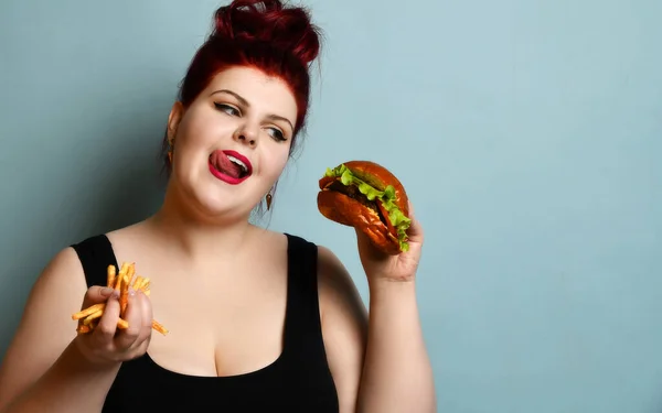 Happy overweight fat woman happy hold burger cheeseburger sandwich met rundvlees en frietjes in de hand — Stockfoto