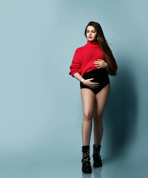 Krásná těhotná dívka v červeném svetru drží její břicho těhotenství, mateřství, lidé a koncept očekávání — Stock fotografie