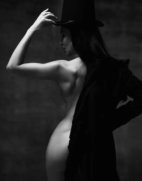 검은 옷을 손에 쥐고 모자를 쓰고 검은 옷을 입고 있는 아름다운 갈색의 소녀 — 스톡 사진