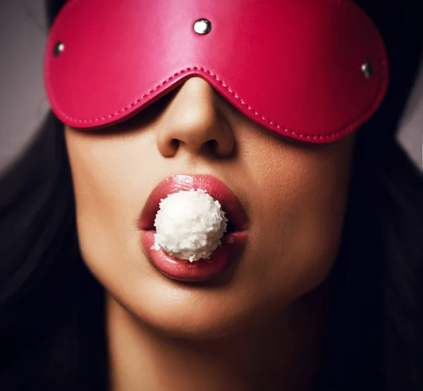 Wanita muda berambut cokelat yang cantik dengan mata tertutup dengan topeng kulit merah muda yang makan permen — Stok Foto