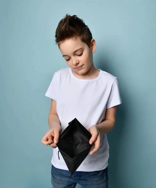 Kleine schattige jongen met modern kapsel in stijlvolle casual kleding staan en tonen lege portemonnee — Stockfoto