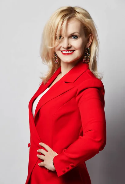 Retrato de jovem bela loira sorrindo mulher feliz sorrindo em elegante terno oficial vermelho profundo elegante e brincos maciços — Fotografia de Stock