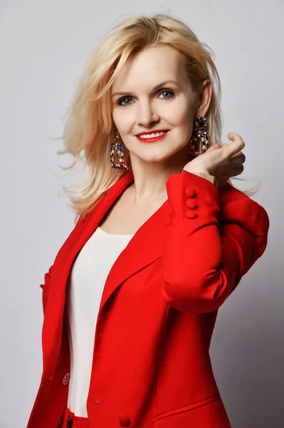 Retrato de jovem bela loira sorrindo mulher feliz sorrindo em elegante terno oficial vermelho profundo elegante e brincos maciços — Fotografia de Stock