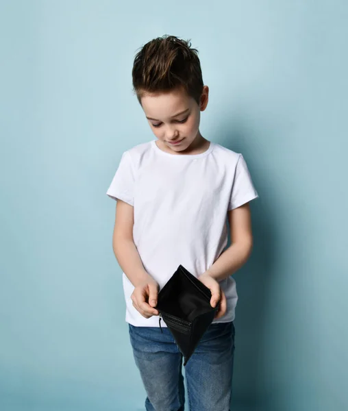 Klein jongetje in wit t-shirt met lege portemonnee over pastelblauwe achtergrond. Niets te betalen voor huisvesting geen geld concept — Stockfoto
