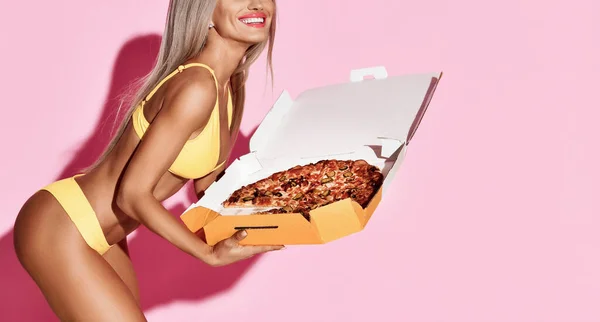 Mulher loira magro bonita segurar grande pizza com pepperoni na caixa de entrega feliz sorrindo em biquíni amarelo — Fotografia de Stock
