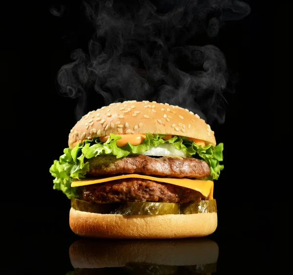 Double burger cheeseburger barbeque sandwich with beef  cheese and fresh vegetables hot with steam smoke on black