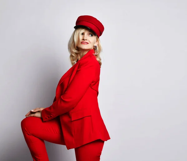 젊은 금발 여성은 우아 한 붉은 정장을 입고 빨간 모자를 쓰고 육중 한 귀를 갖고 있다. — 스톡 사진