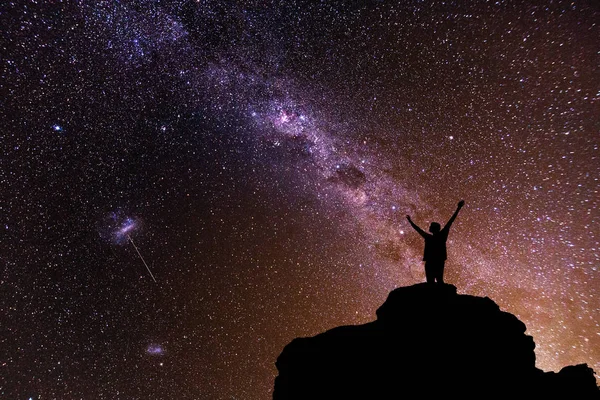 Milky Way. Beautiful night sky with stars and silhouette of a standing alone man on the mountain.