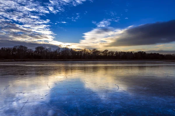 Zugefrorener See im Wald bunte Wolken. — Stockfoto