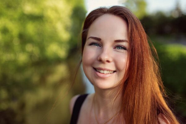 Portrait of red hair girl posing in city park