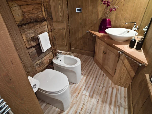 interior photography of a rustic bathroom in the mansard whose floor and walls are made of wood, in foreground the bidet and the toilet bowl