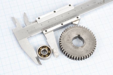 gears and caliper on graph paper background clipart