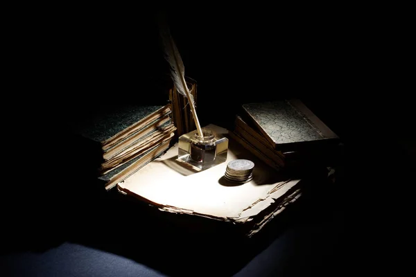 Vieux stylo plume, papiers et encrier et pièces d'argent sur fond noir — Photo