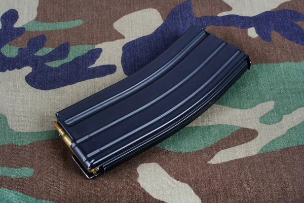 M16 rifle magazine with cartridges on camouflage uniform background