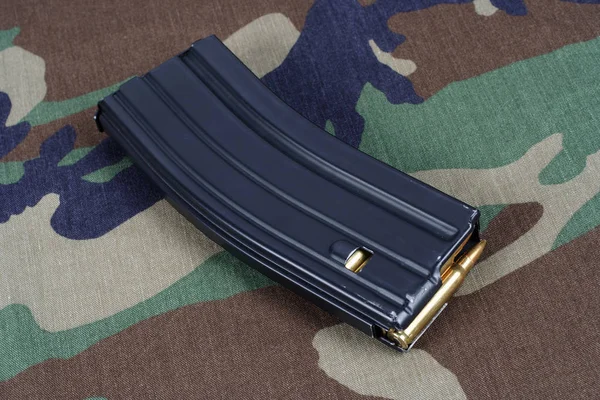 US ARMY M-16 rifle magazine with cartridges on camouflage uniform background