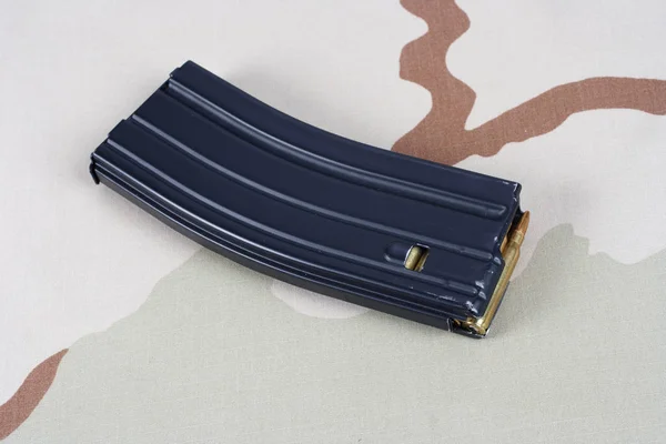 US ARMY M-16 rifle magazine with cartridges on camouflage uniform background