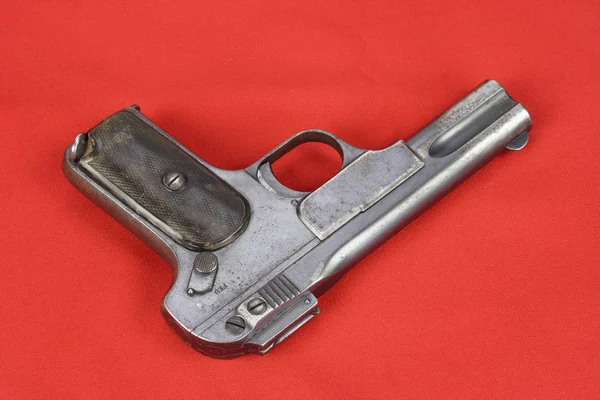 Velha pistola enferrujada no fundo vermelho — Fotografia de Stock