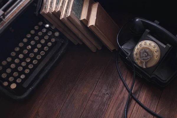 Oude retro telefoon met vintage typemachine en boeken op houten plank — Stockfoto