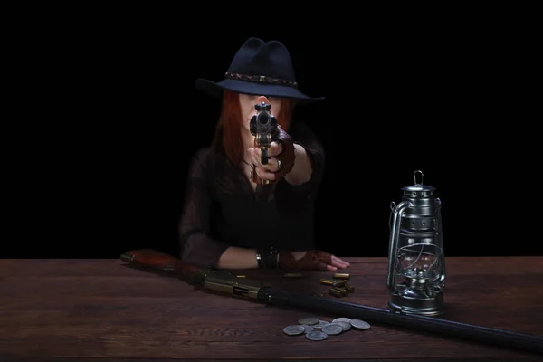 Wild west girl shooting from revolver gun at the table with ammunition and silver coins — ストック写真