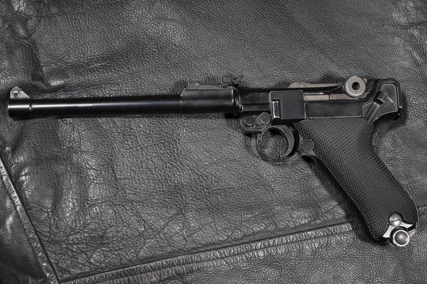 World War I period german army handgun Parabellum "Artillery Luger" on black leather jacket — Stock Photo, Image