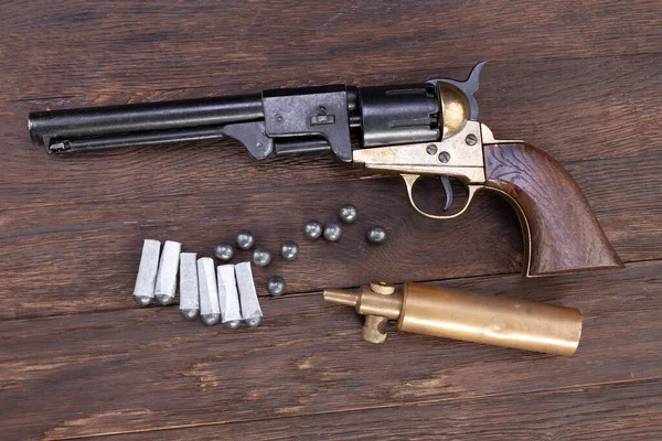 Firearms of the Old West - Percussion Army Revolver with paper cartridges, bullets and powder flask and wooden table