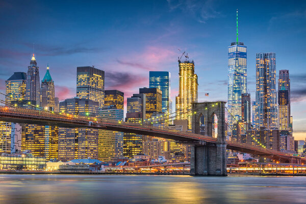 New York City, USA skyline on the East River with Brooklyn Bridge at dusk.