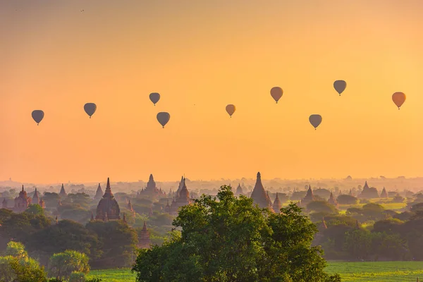 Bagan, Myanmar ancient temple ruins landscape in the archaeological zone at dawn with hot air balloons.
