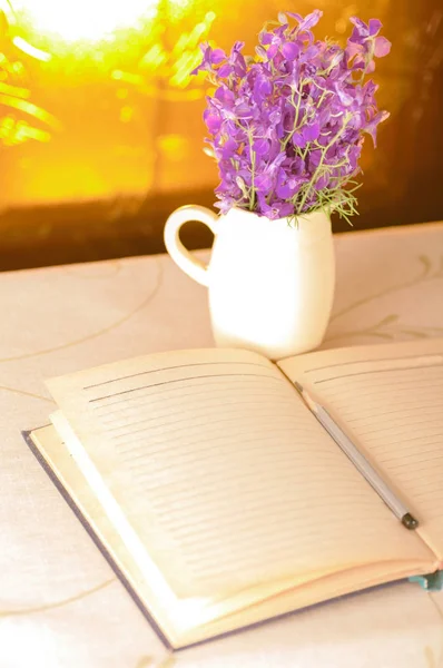 Bloc-notes avec un crayon et un vase avec des fleurs sur la fenêtre bac — Photo