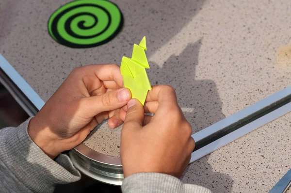 Kind maakt origami uit gekleurd papier close-up — Stockfoto