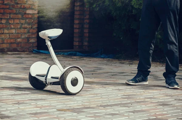 Joven está de pie junto a un scooter eléctrico, un ecológico — Foto de Stock