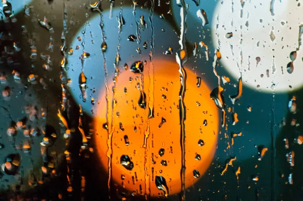 Gouttes de pluie sur le verre la nuit, bokeh coloré, la circulation ligh — Photo