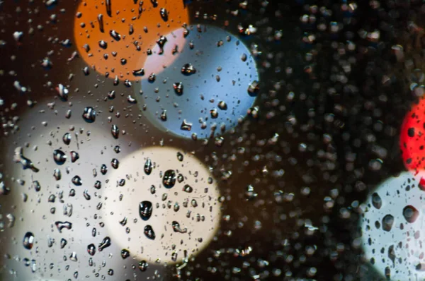 Kapky deště na sklo v noci, barevné bokeh, dopravní ligh — Stock fotografie