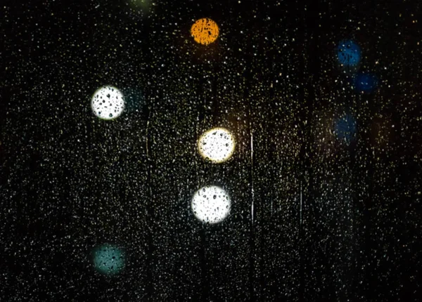 Gouttes de pluie sur le verre la nuit, bokeh coloré, la circulation ligh — Photo