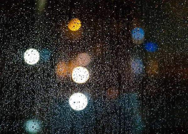 Σταγόνες βροχής στο γυαλί στο νύχτα, χρωματιστά bokeh, ηλεκτρικό κυκλοφορίας — Φωτογραφία Αρχείου