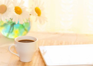 sabah kahve ve bir tablet kahvaltıda, üzerinde bir vazoda papatya