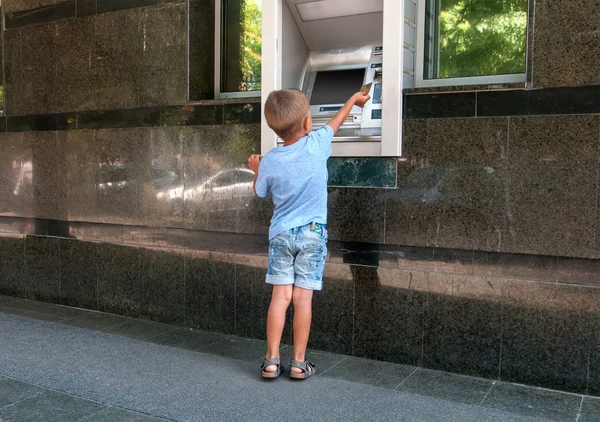 Çocuk para makinesine bir kart yerleştiriyor. — Stok fotoğraf