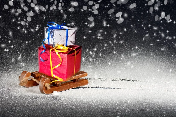 Presentes em um trenó de madeira, neve branca em um fundo preto, Novo — Fotografia de Stock