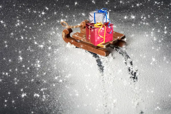 Gifts on a wooden sleigh, trace of a sleigh on white snow on a b — Stock Photo, Image