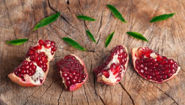 Olgun tanecikli nar dilimleri ve yaşlı kur 'un yeşil yaprakları.