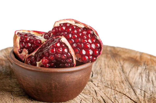 Cloves of pomegranate in a clay plate on an aged wooden backgrou — Stock Photo, Image