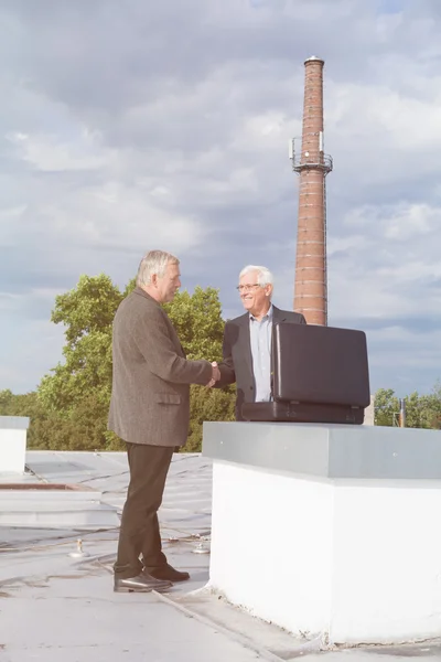 Senior zakenlieden handshaking terwijl het maken van een zakelijke deal op t — Stockfoto