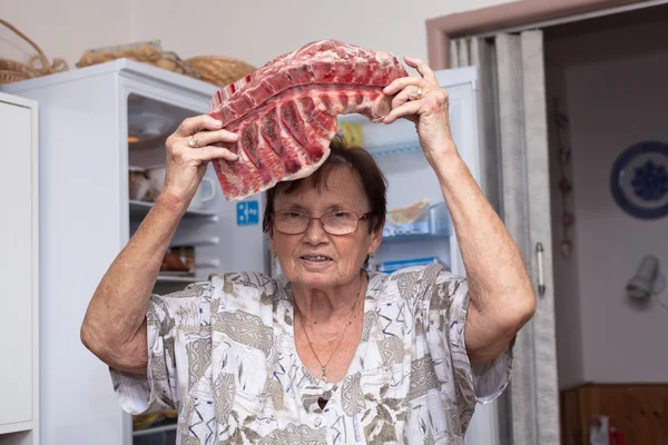Senior woman with raw pork ribs — Stock Photo, Image