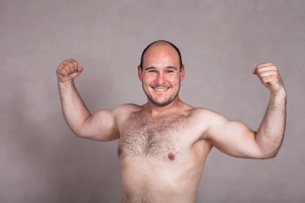 Glücklicher Mann ohne Hemd posiert und zeigt seinen starken Körper Stockbild