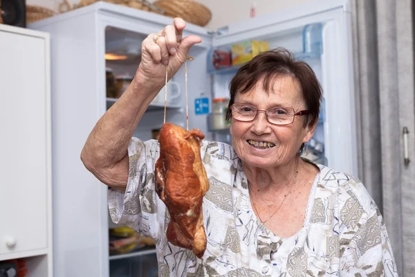 Happy senior woman holding smoked meat Stock Photo